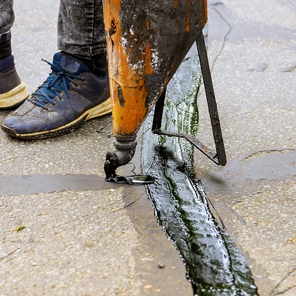 person sealing a crack in the pavement