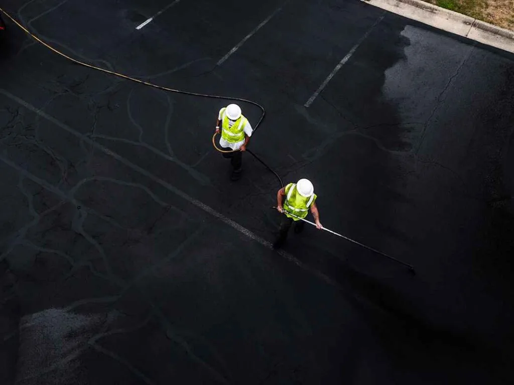 aerial view of two asphalt seal & repair employees sealcoating a street