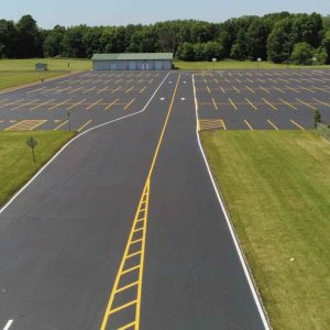 road with yellow pavement markings leading into a parking lot