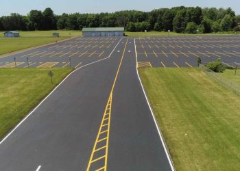 road with yellow pavement markings leading into a parking lot